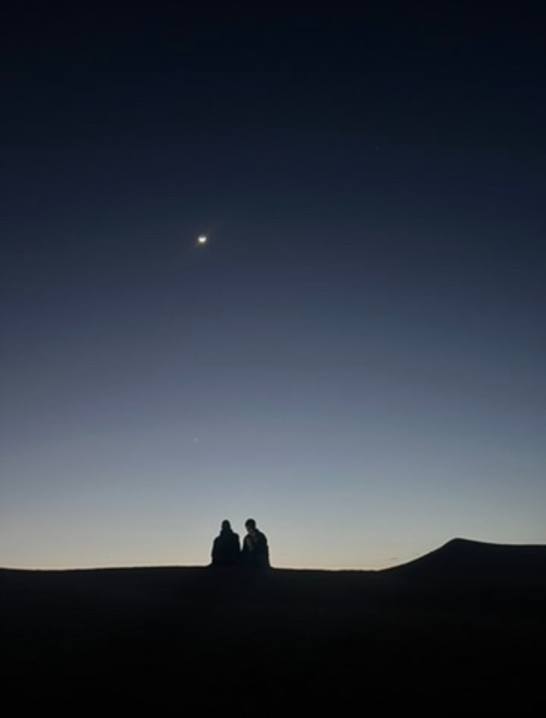 Voyageurs observant les étoiles depuis une dune près de M’Hamid